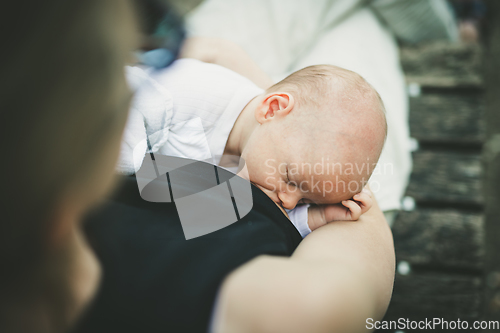 Image of Mother breast feeding and hugging her baby boy outdoors.