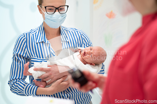 Image of Mother holding her baby boy at medical appointment at pediatrician office.