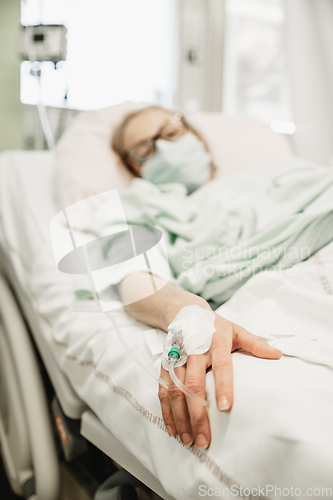 Image of Focus on the woman hand of a patient with medical drip or IV drip in hospital ward , health and medical care concept.