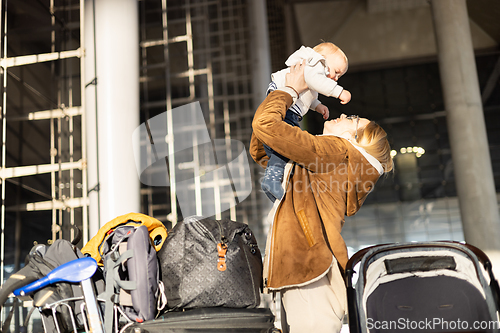 Image of Motherat happily holding and lifting his infant baby boy child in the air after being rejunited in front of airport terminal station. Baby travel concept.