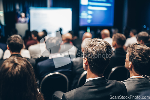 Image of Speaker giving a talk in conference hall at business event. Rear view of unrecognizable people in audience at the conference hall. Business and entrepreneurship concept.