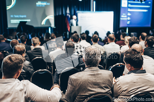 Image of Speaker giving a talk in conference hall at business event. Rear view of unrecognizable people in audience at the conference hall. Business and entrepreneurship concept.