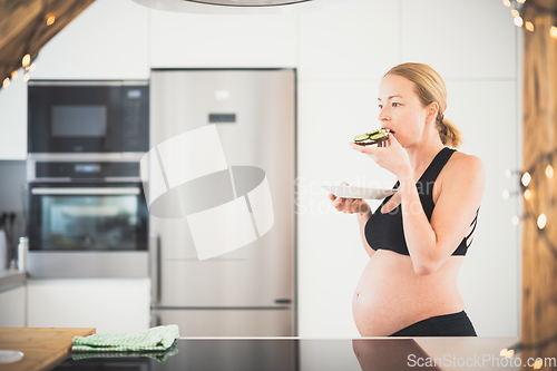 Image of Beautiful sporty fit young pregnant woman having a healthy snack in home kitchen. Healty lifestyle concept.