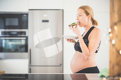 Image of Beautiful sporty fit young pregnant woman having a healthy snack in home kitchen. Healty lifestyle concept.