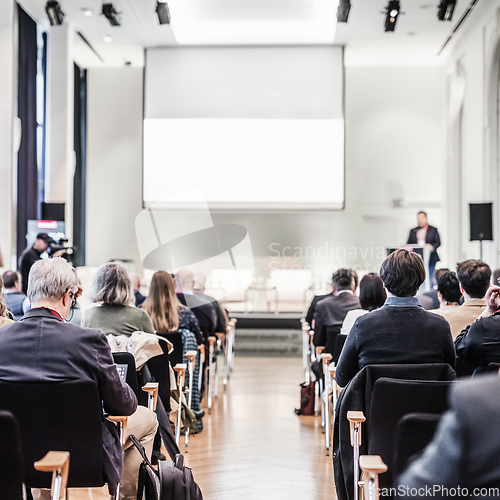 Image of Speaker giving a talk in conference hall at business event. Rear view of unrecognizable people in audience at the conference hall. Business and entrepreneurship concept.