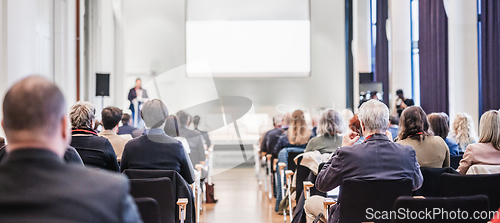 Image of Speaker giving a talk in conference hall at business event. Rear view of unrecognizable people in audience at the conference hall. Business and entrepreneurship concept.