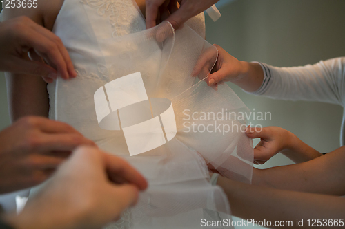 Image of Hands of girlfriends helping the bride to dress her dress