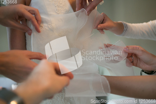 Image of Hands of girlfriends helping the bride to dress her dress