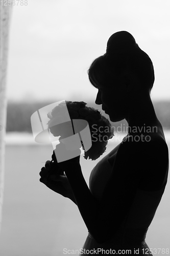 Image of black and white silhouette of the bride weared in dress and veil with a bouquet