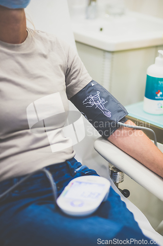 Image of Doctor using sphygmomanometer with stethoscope checking blood pressure to a patient in the hospital.