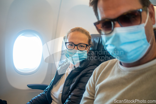 Image of A young couple wearing face masks while traveling on airplane. New normal travel after covid-19 pandemic concept