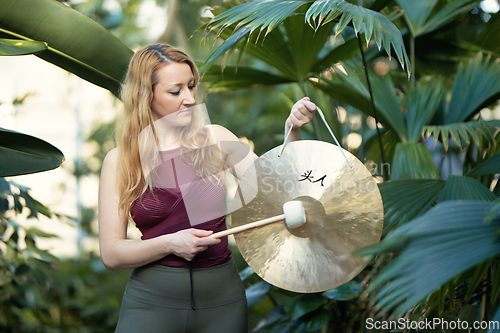 Image of Yoga concept, meditation and sound therapy. Beautiful young caucasian woman performing tibetan gong music therapy.