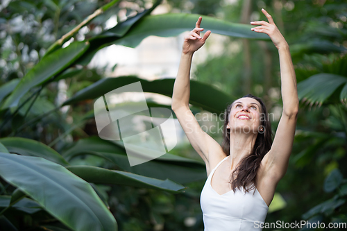 Image of Female meditating and practicing yoga in tropical rainforest. Beautiful young woman practicing yoga outdoor with tropical forest in background.