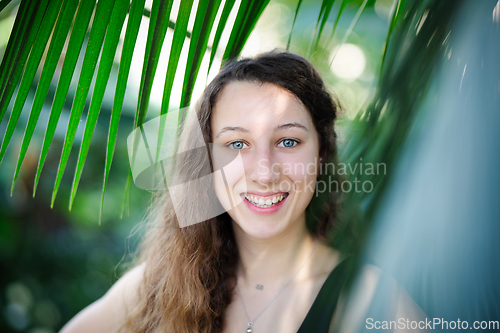 Image of Young beautiful natural cheerful woman with healthy face and skin in exotic greenery. Closeup fresh face of attractive girl. Summer model. Natural beauty concept