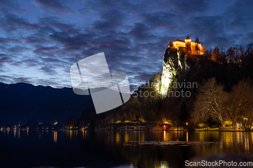 Image of Dramatic cloudscape over medieval castle of Bled perched on cliff above Bled lake at dusk, Slovenia.