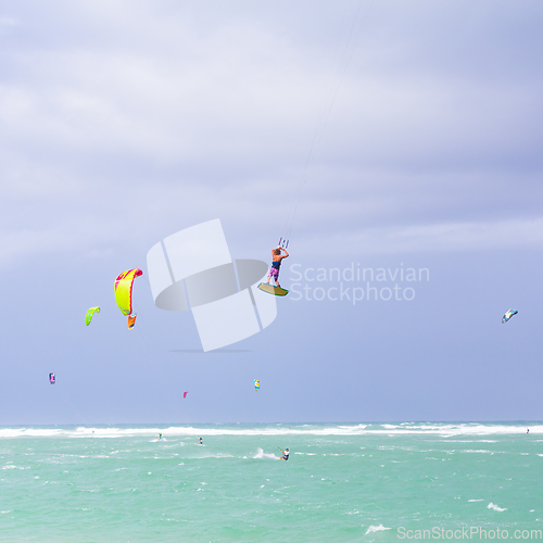 Image of Kiteboarding. Fun in the ocean. Extreme Sport Kitesurfing. Kitesurfer jumping high in the air performing triks during kitesurfing session.