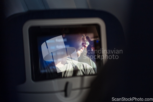 Image of Reflection of a passenger on an airplane touch screen monitor during long flight. Entertainment service system in aircraft.