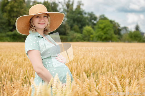 Image of Pregnant woman in hat in field of wheat