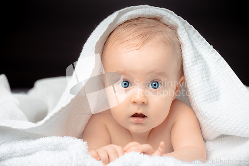 Image of Cute baby with blue eyes lying on bed