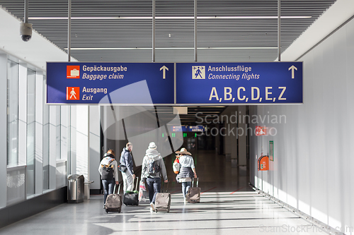 Image of Unrecognizable People With Bags And Suitcase Walking In Airport Terminal. Rear View Of Passengers On Their Way To Flight Boarding Gate, Ready For Business Travel Or Vacation Journey.