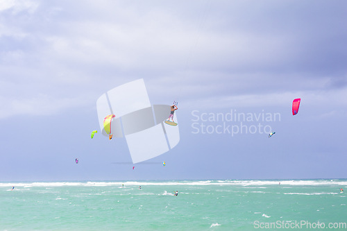 Image of Kiteboarding. Fun in the ocean. Extreme Sport Kitesurfing. Kitesurfer jumping high in the air performing triks during kitesurfing session.