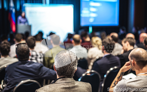 Image of Speaker giving a talk in conference hall at business event. Rear view of unrecognizable people in audience at the conference hall. Business and entrepreneurship concept.