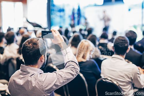 Image of Speaker giving a talk in conference hall at business event. Rear view of unrecognizable people in audience at the conference hall. Business and entrepreneurship concept.