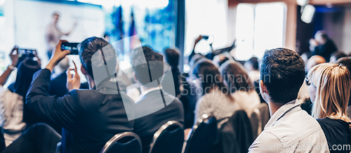 Image of Speaker giving a talk in conference hall at business event. Rear view of unrecognizable people in audience at the conference hall. Business and entrepreneurship concept.