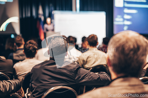 Image of Speaker giving a talk in conference hall at business event. Rear view of unrecognizable people in audience at the conference hall. Business and entrepreneurship concept.