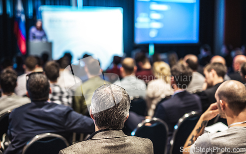 Image of Speaker giving a talk in conference hall at business event. Rear view of unrecognizable people in audience at the conference hall. Business and entrepreneurship concept.