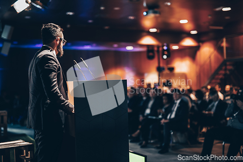 Image of Speaker giving a talk on corporate business conference. Unrecognizable people in audience at conference hall. Business and Entrepreneurship event