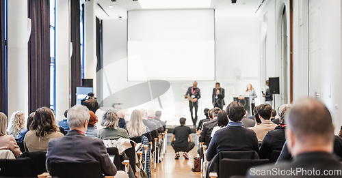 Image of Business team leader receiving award prize at best business project competition event. Business and entrepreneurship award ceremony theme. Focus on unrecognizable people in audience.