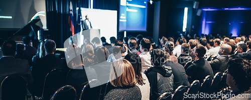 Image of Speaker giving a talk in conference hall at business event. Rear view of unrecognizable people in audience at the conference hall. Business and entrepreneurship concept.