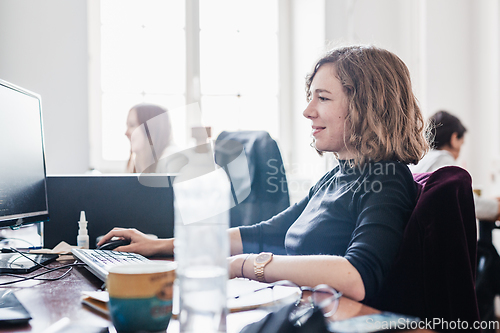 Image of Yound devoted female software developers team working on desktop computer in IT statup company.