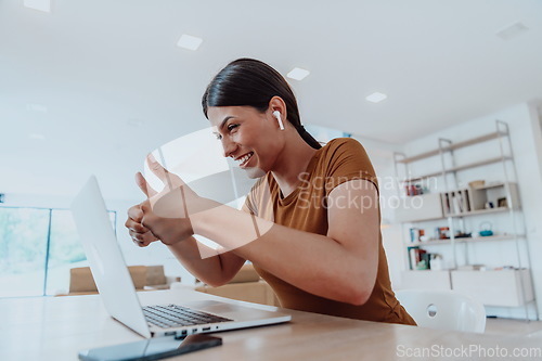 Image of Woman sitting in living room using laptop look at cam talk by video call with business friend relatives, head shot. Job interview answering questions.