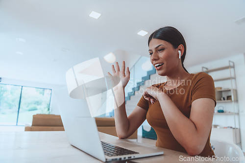 Image of Woman sitting in living room using laptop look at cam talk by video call with business friend relatives, head shot. Job interview answering questions.