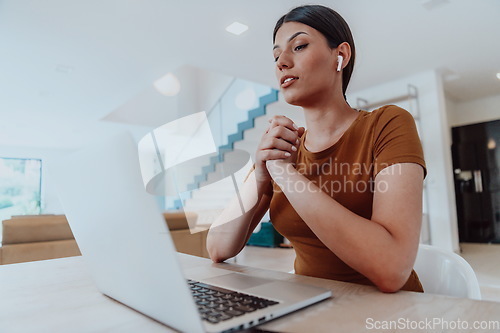 Image of Woman sitting in living room using laptop look at cam talk by video call with business friend relatives, head shot. Job interview answering questions.