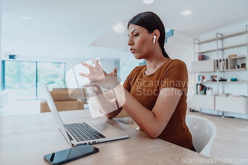 Image of Woman sitting in living room using laptop look at cam talk by video call with business friend relatives, head shot. Job interview answering questions.