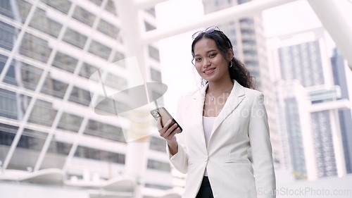 Image of Asian executive working woman holding and using mobile phone in the street