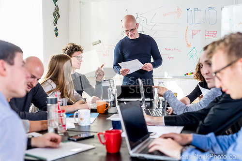 Image of Startup business and entrepreneurship problem solving. Young AI programmers and IT software developers team brainstorming and programming on desktop computer in startup company share office space.