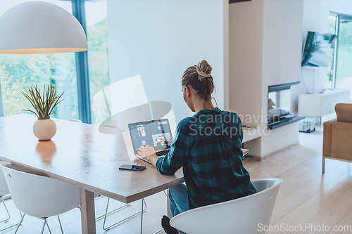 Image of Woman sitting in living room using laptop look at cam talk by video call with business friend relatives, head shot. Job interview answering questions.