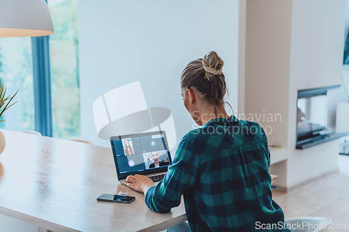 Image of Woman sitting in living room using laptop look at cam talk by video call with business friend relatives, head shot. Job interview answering questions.