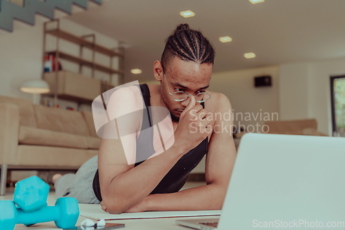 Image of Training At Home. Sporty man doing training while watching online tutorial on laptop, exercising in living room, free space