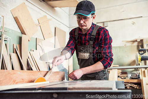 Image of Carpenter worker cutting wooden board