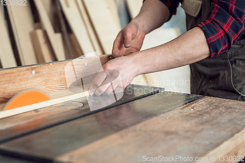 Image of Construction worker cutting wooden board