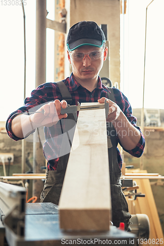 Image of The worker makes measurements of a wooden board