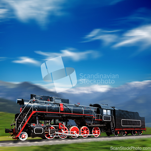 Image of Speeding old locomotive in mountains with motion blur