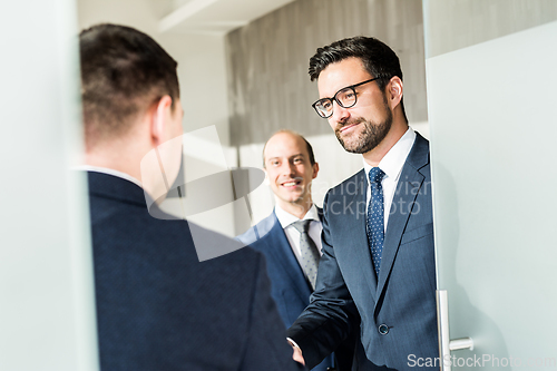 Image of Group of confident business people greeting with a handshake at business meeting in modern office or closing the deal agreement by shaking hands.