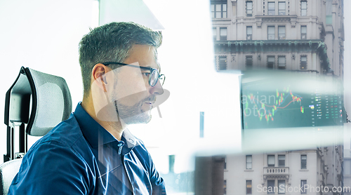 Image of Stock broker trading online watching charts and data analyses on multiple computer screens.