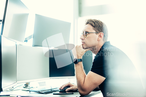 Image of Stock broker trading online watching charts and data analyses on multiple computer screens.